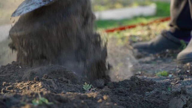 Digging garden soil with shovel in slow motion close-up