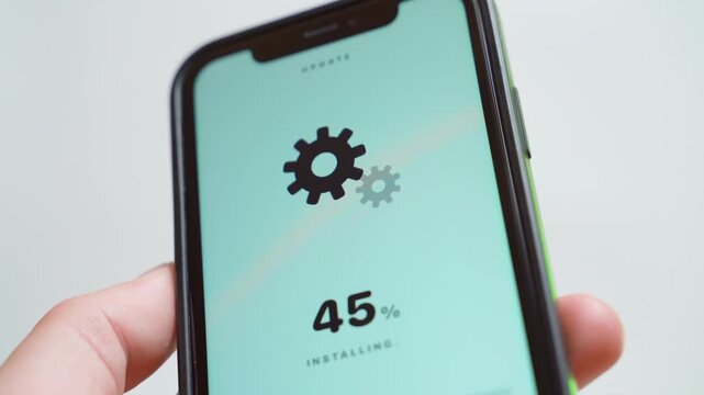 Software update downloading on smartphone screen with gear icons close-up. Loading progress percentage in hand