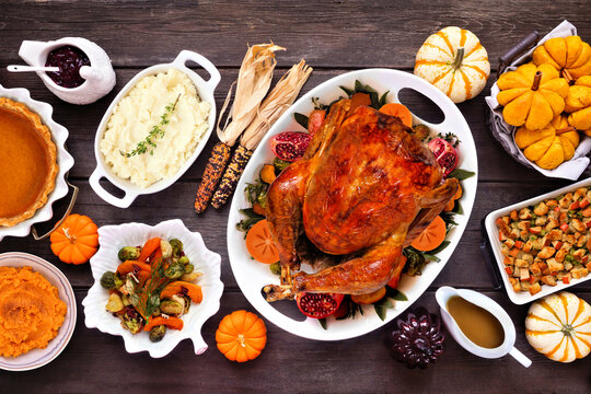 Thanksgiving turkey dinner. Above view table scene on a rustic dark wood table background. Turkey, mashed potatoes, stuffing, pumpkin pie and sides.
