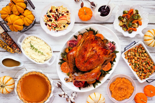 Thanksgiving turkey dinner. Top down view table scene on a rustic white wood table background. Turkey, mashed potatoes, stuffing, pumpkin pie and sides.