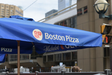 Obraz premium patio umbrella with Boston Pizza branding outside the pizza restaurant chain, located here at 250 Front St W, Toronto