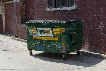 Fototapeta premium WM commercial wheeled waste container with a split (two-flap) lid in a lane in Toronto