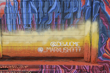 Fototapeta premium brick wall with mural signed by @dewucme and @_markush777, near Graffiti Alley, Toronto