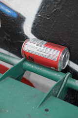 Fototapeta premium discarded can of Coca-Cola, ingredients list, between a wall and a green bin handle in Toronto
