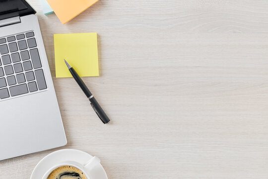 Laptop coffee and one sticky note on a clean desk for quiet productivity