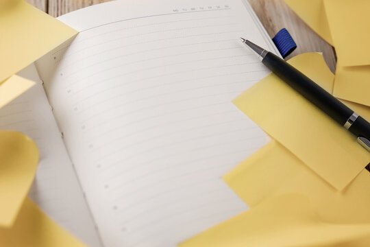 Open hourly planner with a pen and yellow sticky notes for a task list