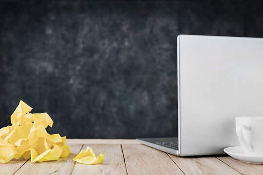 Crumpled sticky notes sit beside a closed laptop and coffee with copy space