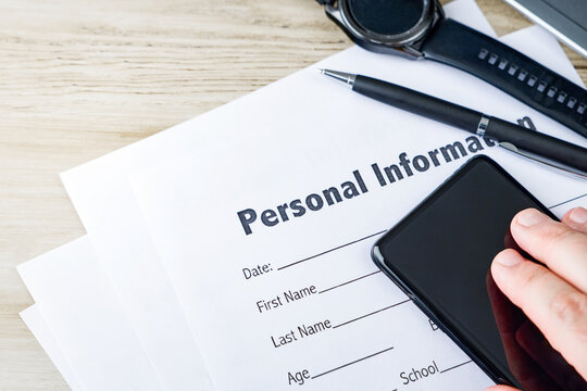 Hand uses a smartphone beside a personal information form for data privacy