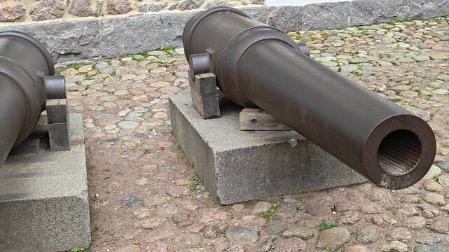A cannon sitting on top of a cement block, potentially abandoned or used for decorative purposes