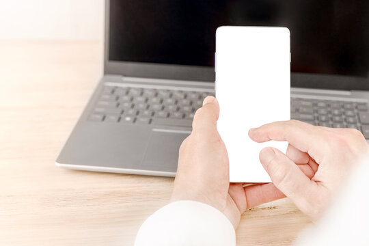 Hands hold a blank smartphone in front of a laptop for AI digital trust