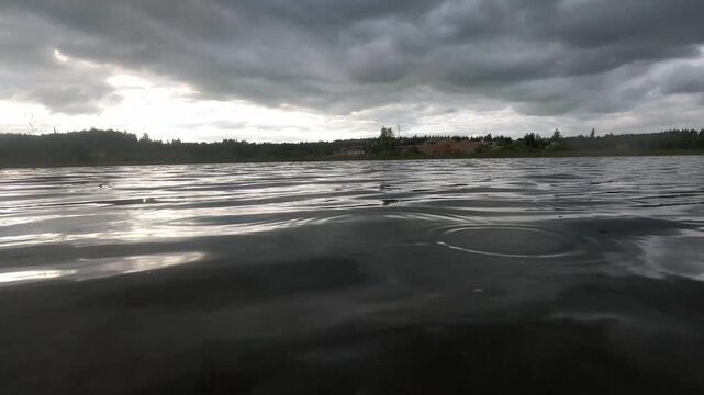 Rippling water reflecting light beneath dark storm clouds