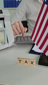Working on tax calculations at a desk with cash and an American flag in view during the tax season