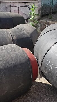 Large black pipes are arranged in a yard with measurements visible on some sections