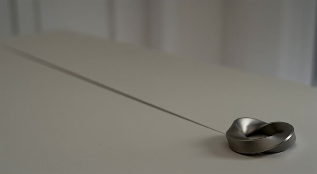 Luxury ambient light wallpaper: silver Mobius loop with over 80% negative space catching sunlight shadow.
