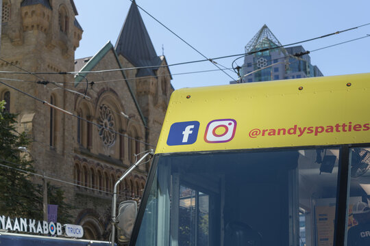 detail of a Randy&rsquo;s Patties, a Toronto Jamaican patty food truck at a TIFF 2026 activation with defocused St Andrew's Presbyterian Church, King St W and Simcoe St