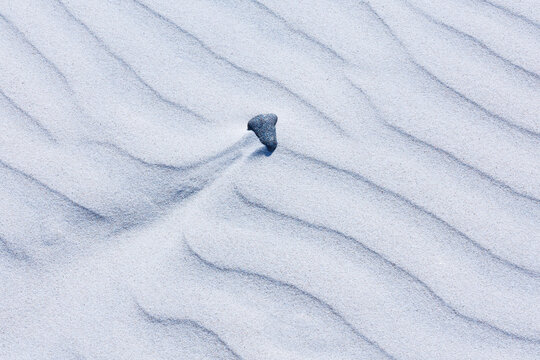 Close-up abstract of perfect wind ripple patterns in white sand dunes forming gentle waves