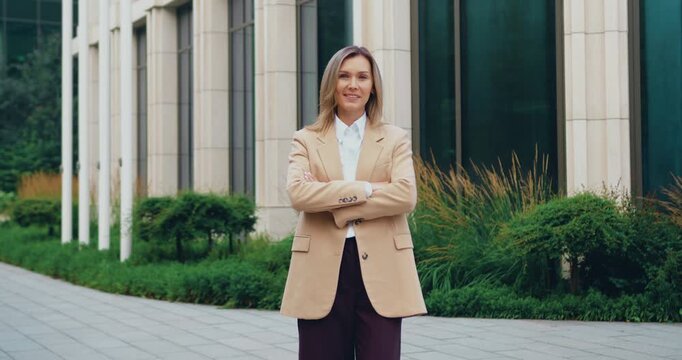 Portrait of a beautiful Caucasian woman with long hair wearing suit, smiling and looking at the camera outdoors on a sunny summer day