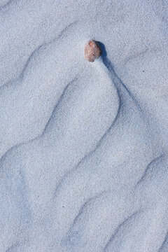 Close-up abstract of perfect wind ripple patterns in white sand dunes forming gentle waves