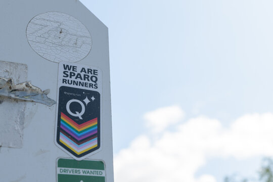 old stickers on the back of a traffic sign, including that of &ldquo;We Are Sparq Runners&rdquo; in Toronto