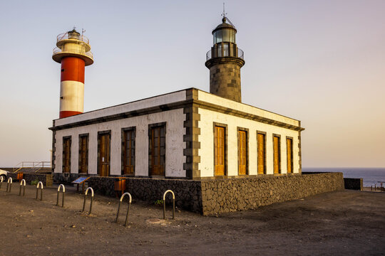 Vista en &aacute;ngulo del antiguo faro de piedra y el nuevo faro de rayas rojas y blancas en Fuencaliente, La Palma, a la luz del atardecer.