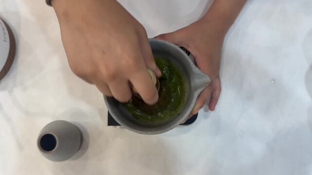 Barista whisking green matcha tea in ceramic bowl with bamboo whisk on counter for cafe and beverage banner, horizontal