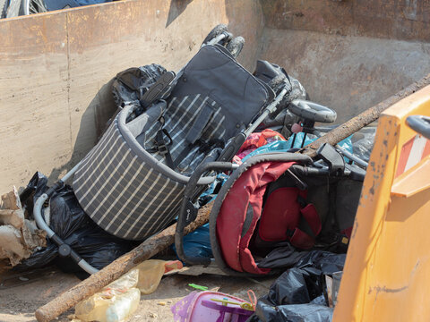 Discarded Baby Strollers Thrown Away in a Large Metal Dumpster