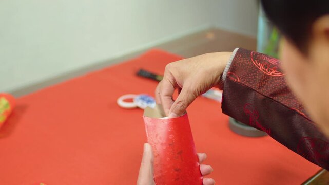 Hands Holding Red Chinese Calligraphy Scroll on Table for Lunar New Year Celebration