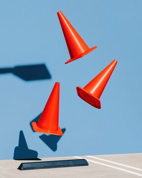 Orange parking cones levitating in mid-air against a vibrant blue background, featuring crisp shadows and a clean mockup for graphic design