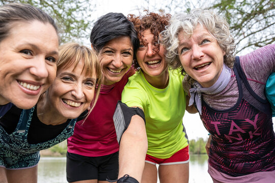 Group of generation x and baby boomer women smiling together after outdoor exercise. Energetic friends in sportswear celebrate fitness, friendship, active aging, and healthy lifestyle.