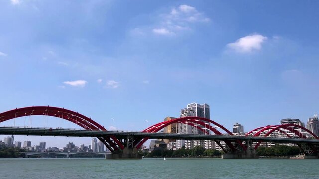 Red Arch Bridge Over River With City Skyline And Blue Sky in Guangzhou, China