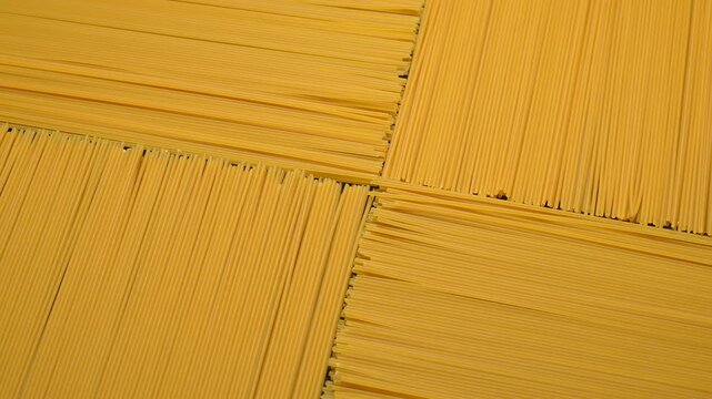 Flat lay texture of dry raw spaghetti arranged in perpendicular blocks.