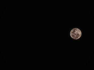 Stunning full moon glowing in a pure black night sky. Detailed lunar craters with a warm pinkish tint © MuhammadRizki