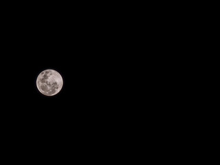 Stunning full moon glowing in a pure black night sky. Detailed lunar craters with a warm pinkish tint © MuhammadRizki