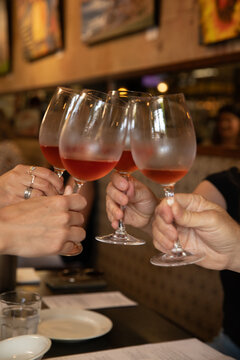 four hands toasting with glass of wine in a bistro