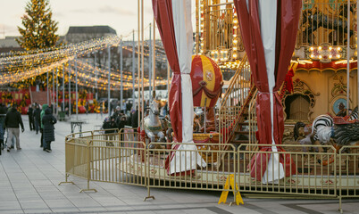 Christmas carousel with colorful animal figures at Cathedral Square in Vilnius, Lithuania. Festive amusement ride and holiday lights create a cheerful winter atmosphere. © MNStudio