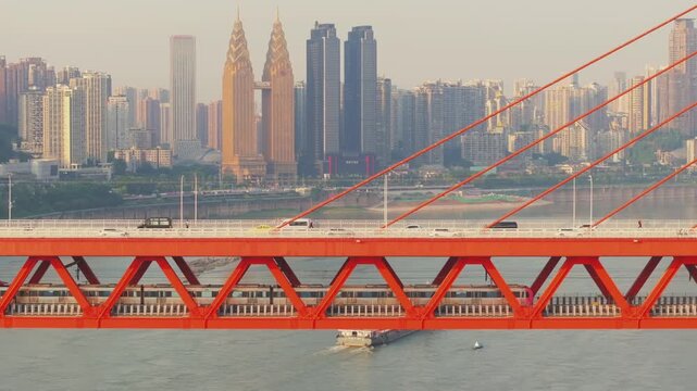 Red suspension bridge spanning river in Chongqing China with city skyline