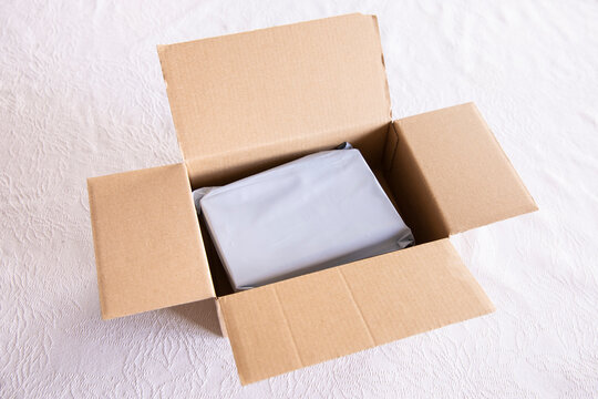 An open shipping cardboard box containing a wrapped item, ready for delivery, e-commerce, and online shopping concept.