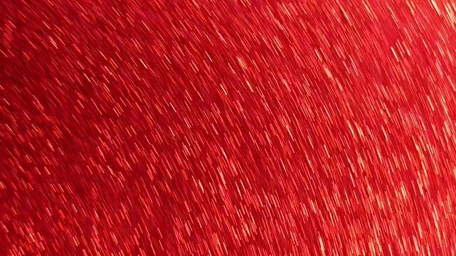 Red glitter paper rapidly waved in front of the camera, creating shimmering reflections, motion blur and a rippling sparkling effect across the frame.
