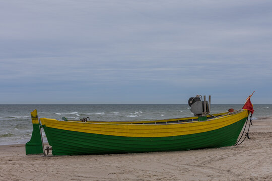Vibrant green and yellow wooden fishing boat parked on Polish Baltic beach sand