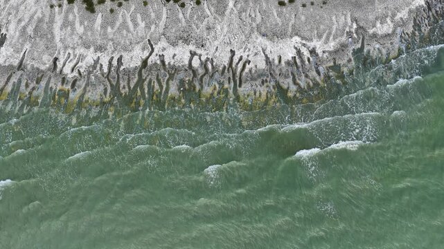 An aerial view of the white, salty soil exposed as the water level in Lake Burdur receded due to drought, and the waves crashing against the shore.