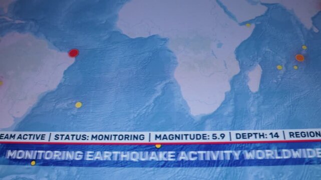 Close camera shot computer monitor screen earthquake monitoring data seismic event markers magnitude depth scrolling alert ticker. Visible screen pixels and scan lines emphasize recorded-monitor 