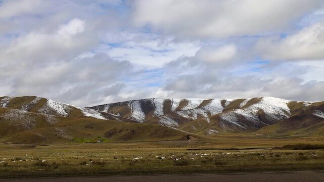 Snow-Capped Mountains Over Grassy Plains Under Cloudy Sky