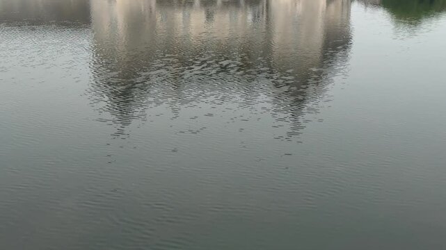 Shimmering reflection of Ch&acirc;teau de la Roche Courbon distorted by gentle ripples on the surface of a mirror pool in Saint-Porchaire, France.
