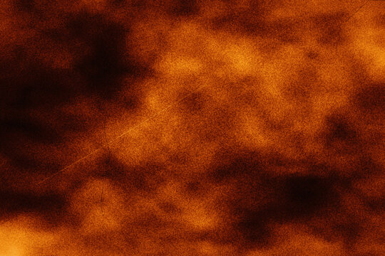 Abstract warm orange and dark brown grunge textured surface background with light scratches for design elements or overlay effects.