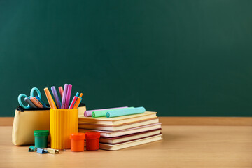Different stationery on wooden table near chalkboard, space for text © New Africa