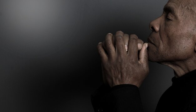 A serene portrait of a man praying with hands together in deep prayer that perfectly captures themes of faith, hope, mindfulness, and inner peace stock image stock photo