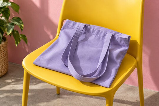 Lavender canvas tote bag on yellow chair against pink wall