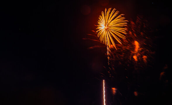 A bright firework explodes in the night sky over the city during a celebration. People gather to watch and enjoy the show.