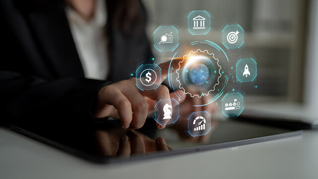 A businesswoman interacts with a tablet displaying financial technology icons in a modern office, symbolizing innovation and data analysis in the business sector. Nascent