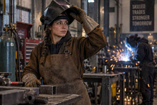 Female Welding Apprentice Adjusting Protective Helmet in Workshop